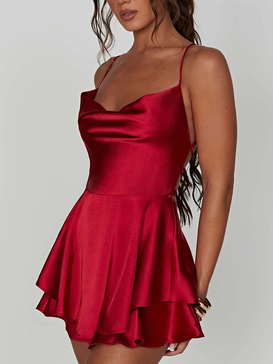 Kurzer Satin-Jumpsuit mit Wasserfallausschnitt, Spaghettiträgern und Rückenschnürung – leicht, elegant und ideal für warme Tage oder lange Nächte.