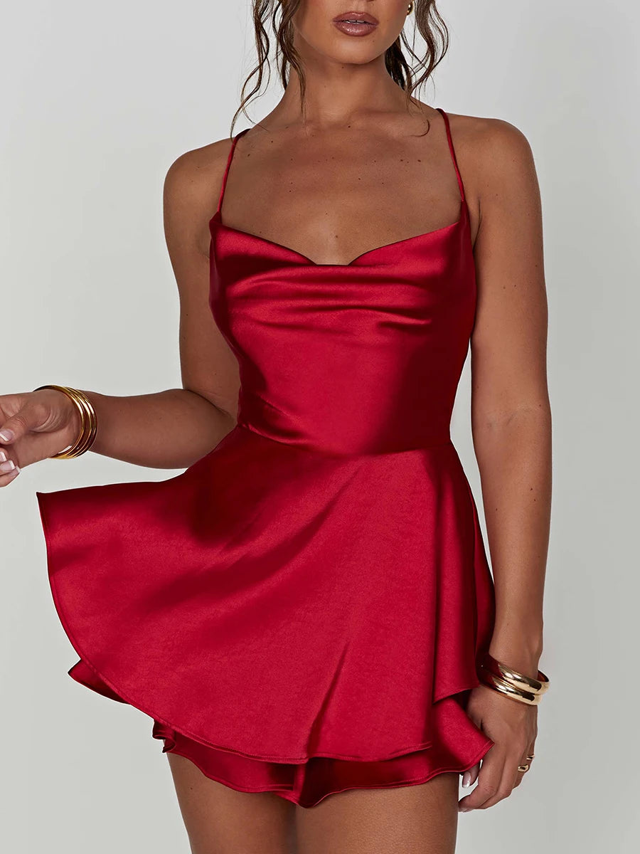 Kurzer Satin-Jumpsuit mit Wasserfallausschnitt, Spaghettiträgern und Rückenschnürung – leicht, elegant und ideal für warme Tage oder lange Nächte.