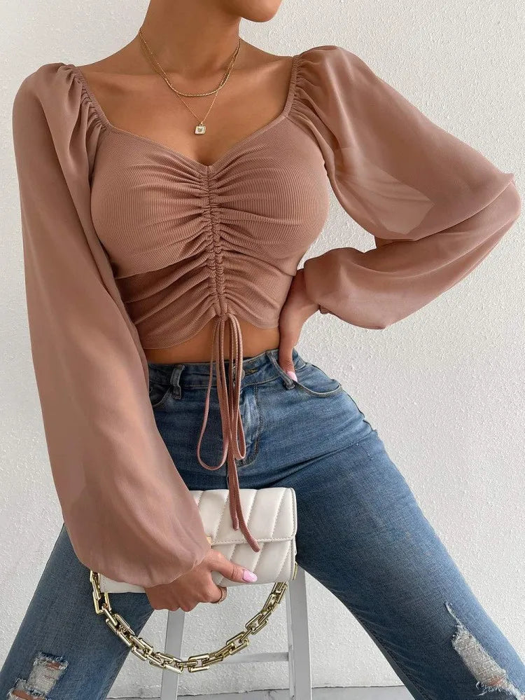 Mesh-Top mit langen Puffärmeln, Wickeloptik und Tunnelzug – bauchfrei, figurbetont und ideal für auffällige Layering-Looks.