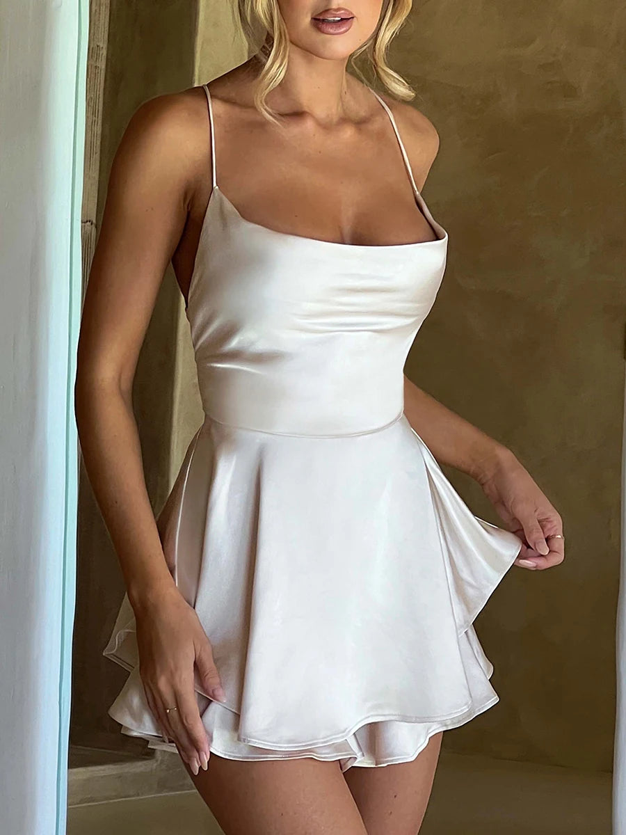 Kurzer Satin-Jumpsuit mit Wasserfallausschnitt, Spaghettiträgern und Rückenschnürung – leicht, elegant und ideal für warme Tage oder lange Nächte.